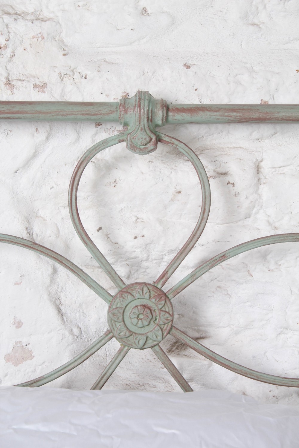 A pair of antique single iron bed frames featuring curved Celtic loop motifs on the headboards and a distressed painted finish. View III