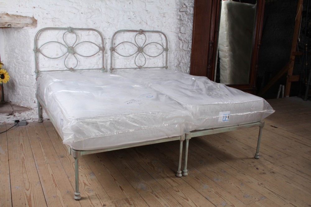 A pair of antique single iron bed frames featuring curved Celtic loop motifs on the headboards and a distressed painted finish. View VI