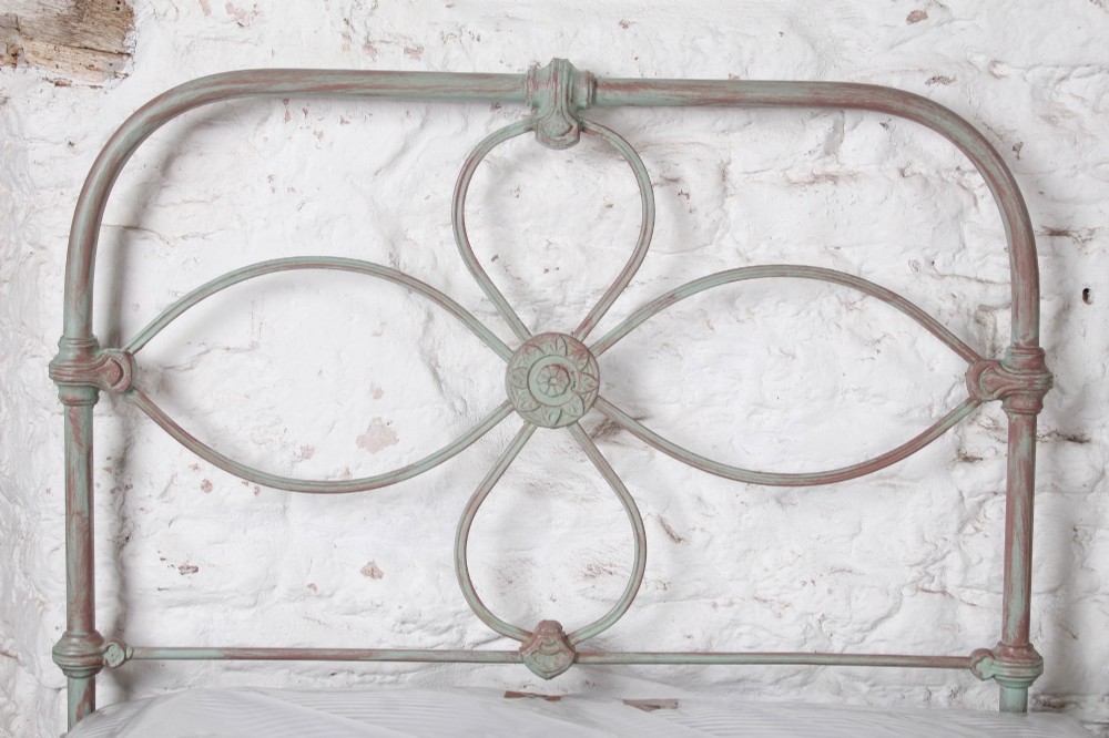 A pair of antique single iron bed frames featuring curved Celtic loop motifs on the headboards and a distressed painted finish. View VIII