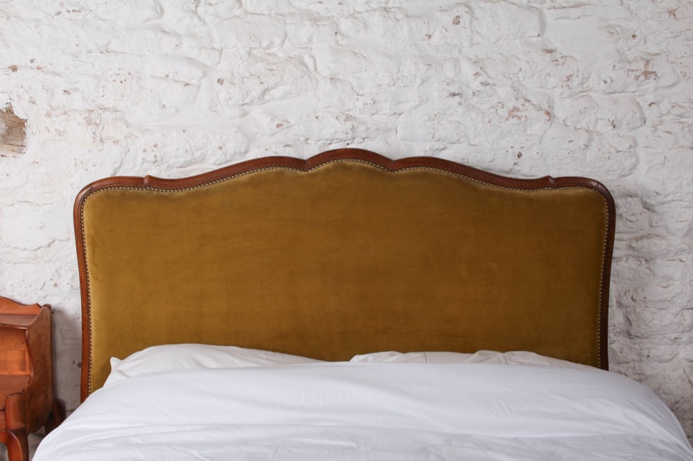 A French double bed frame crafted with a contoured dark wood border, olive velvet upholstery, brass stud trim, and cabriole legs. View II