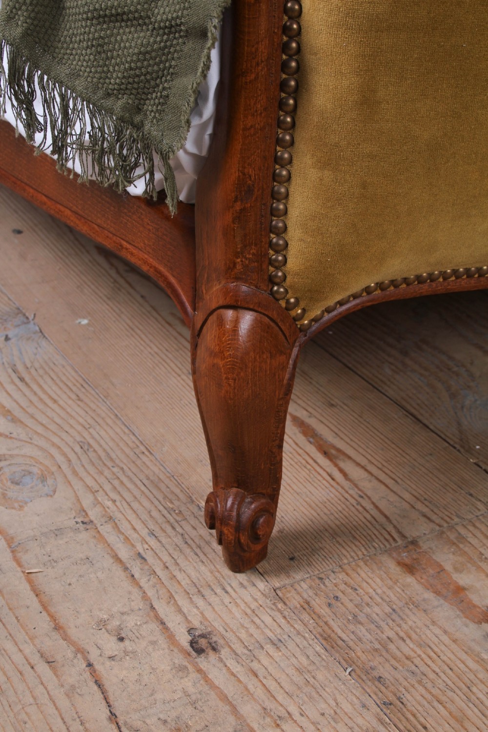 A French double bed frame crafted with a contoured dark wood border, olive velvet upholstery, brass stud trim, and cabriole legs. View V