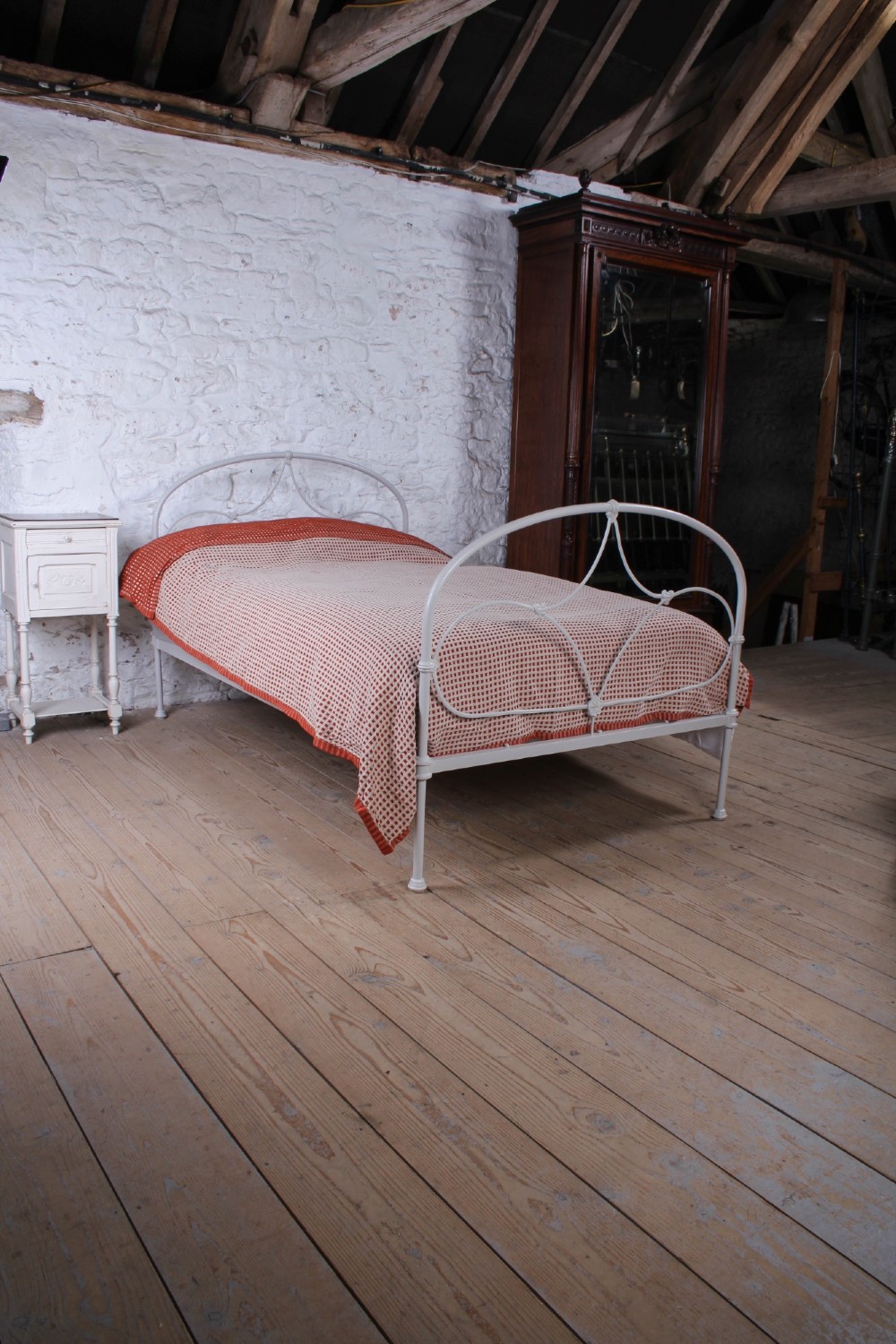 An off-white painted iron bedstead featuring a curved headboard and footboard with Celtic-style decorative metal scrollwork. View III