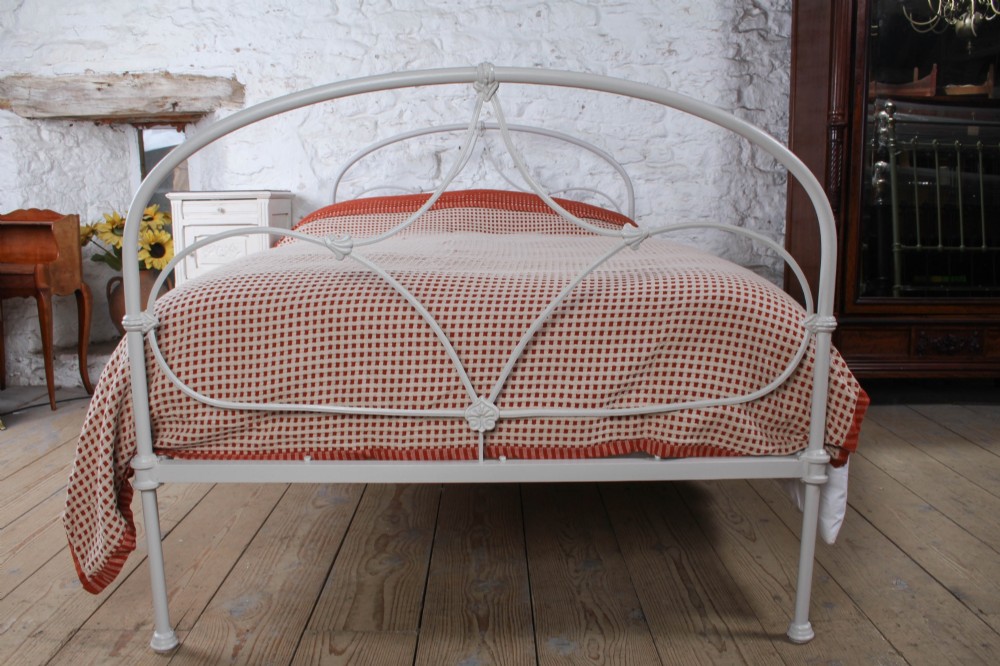 An off-white painted iron bedstead featuring a curved headboard and footboard with Celtic-style decorative metal scrollwork. View IV