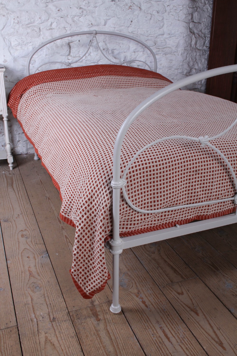 An off-white painted iron bedstead featuring a curved headboard and footboard with Celtic-style decorative metal scrollwork. View VI