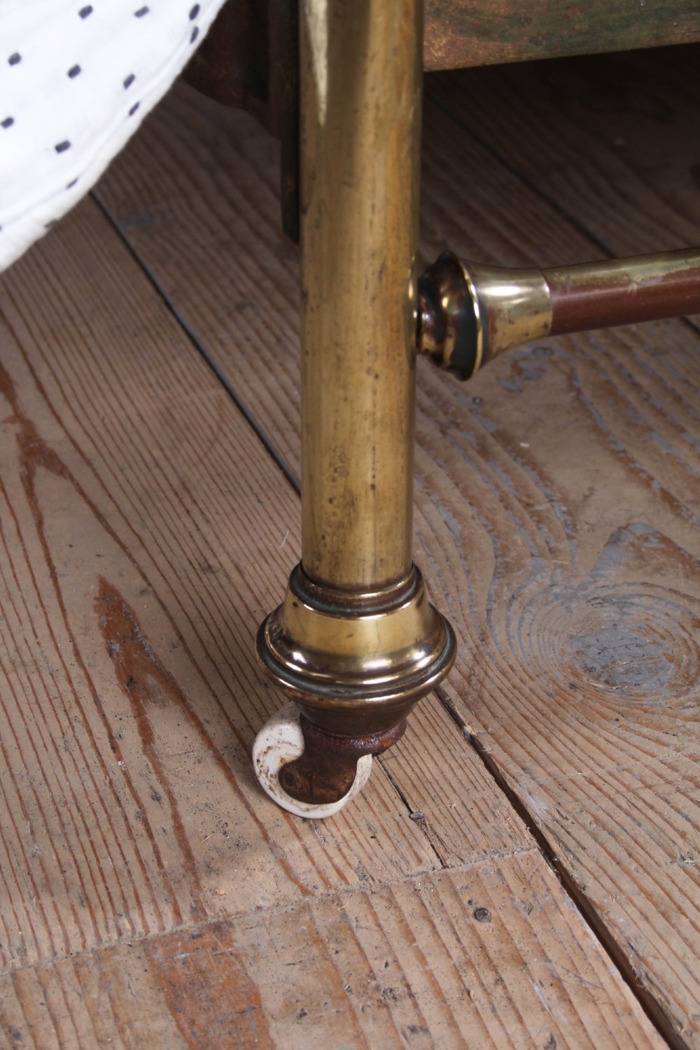 An antique French all-brass double bed frame featuring a rounded headboard and footboard with slender vertical spindles set on castor wheels. View IV