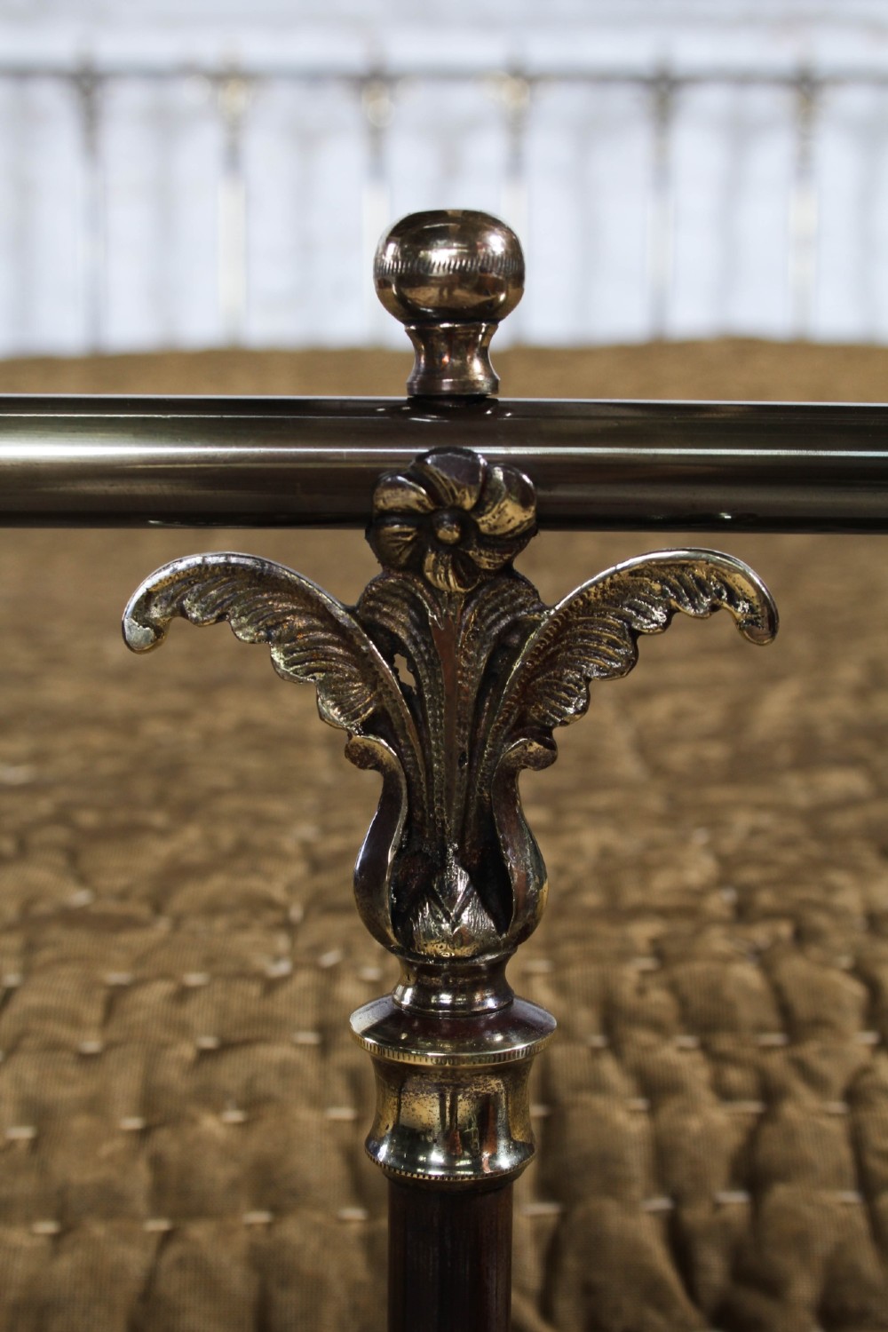 An antique Victorian brass king-size bedstead featuring vertical tubular spindles, decorative cast connectors, top rail ball finials, and original white ceramic castors. View V