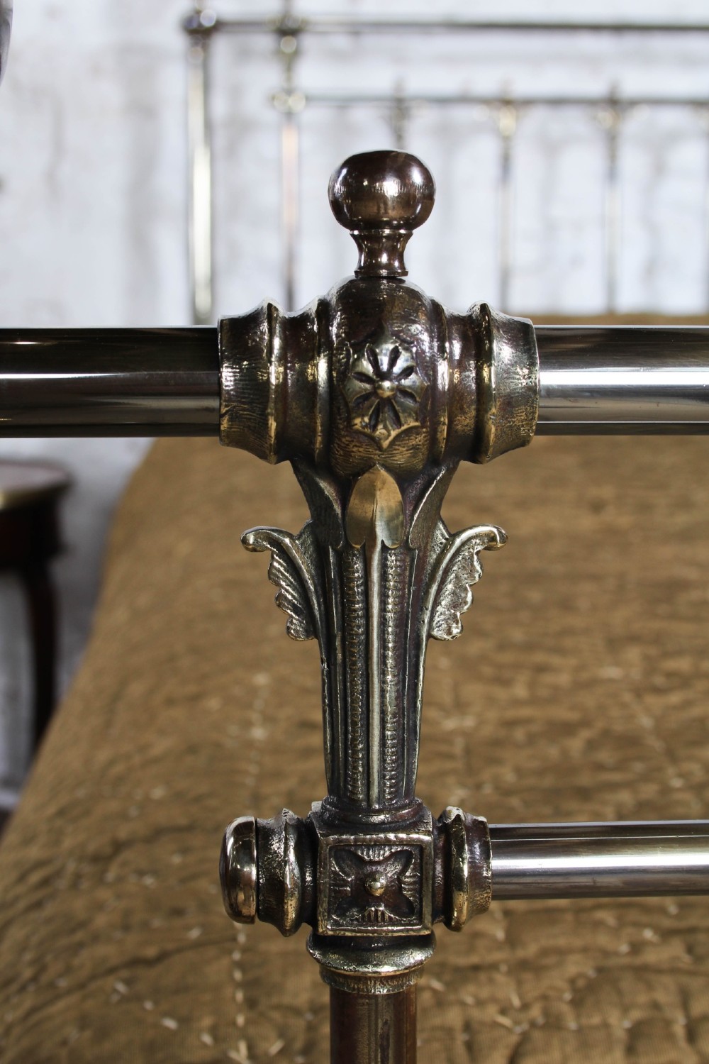 An antique Victorian brass king-size bedstead featuring vertical tubular spindles, decorative cast connectors, top rail ball finials, and original white ceramic castors. View VI