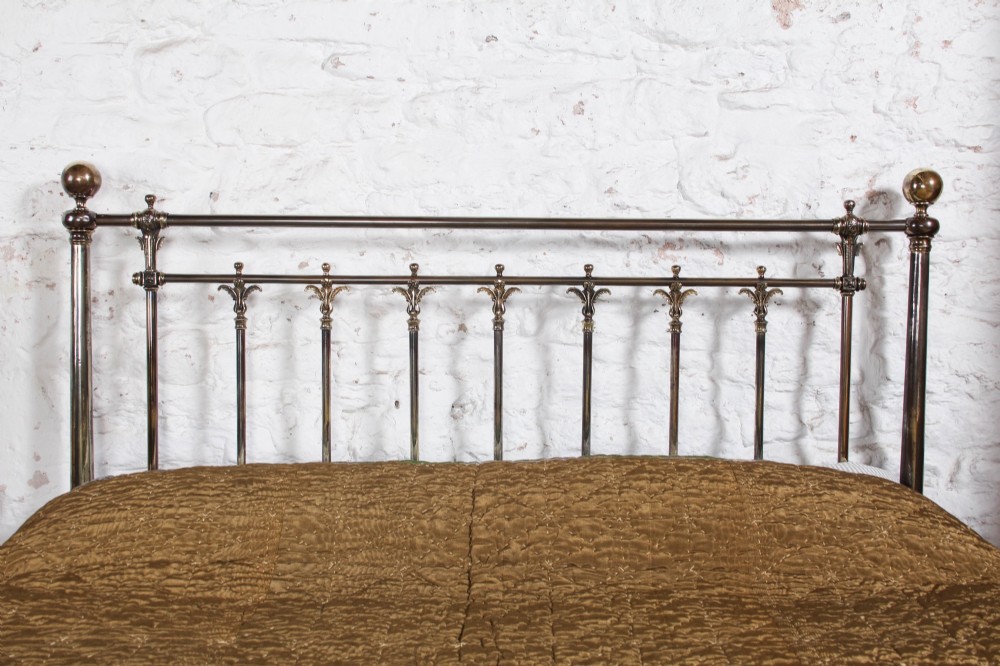 An antique Victorian brass king-size bedstead featuring vertical tubular spindles, decorative cast connectors, top rail ball finials, and original white ceramic castors. View VIII