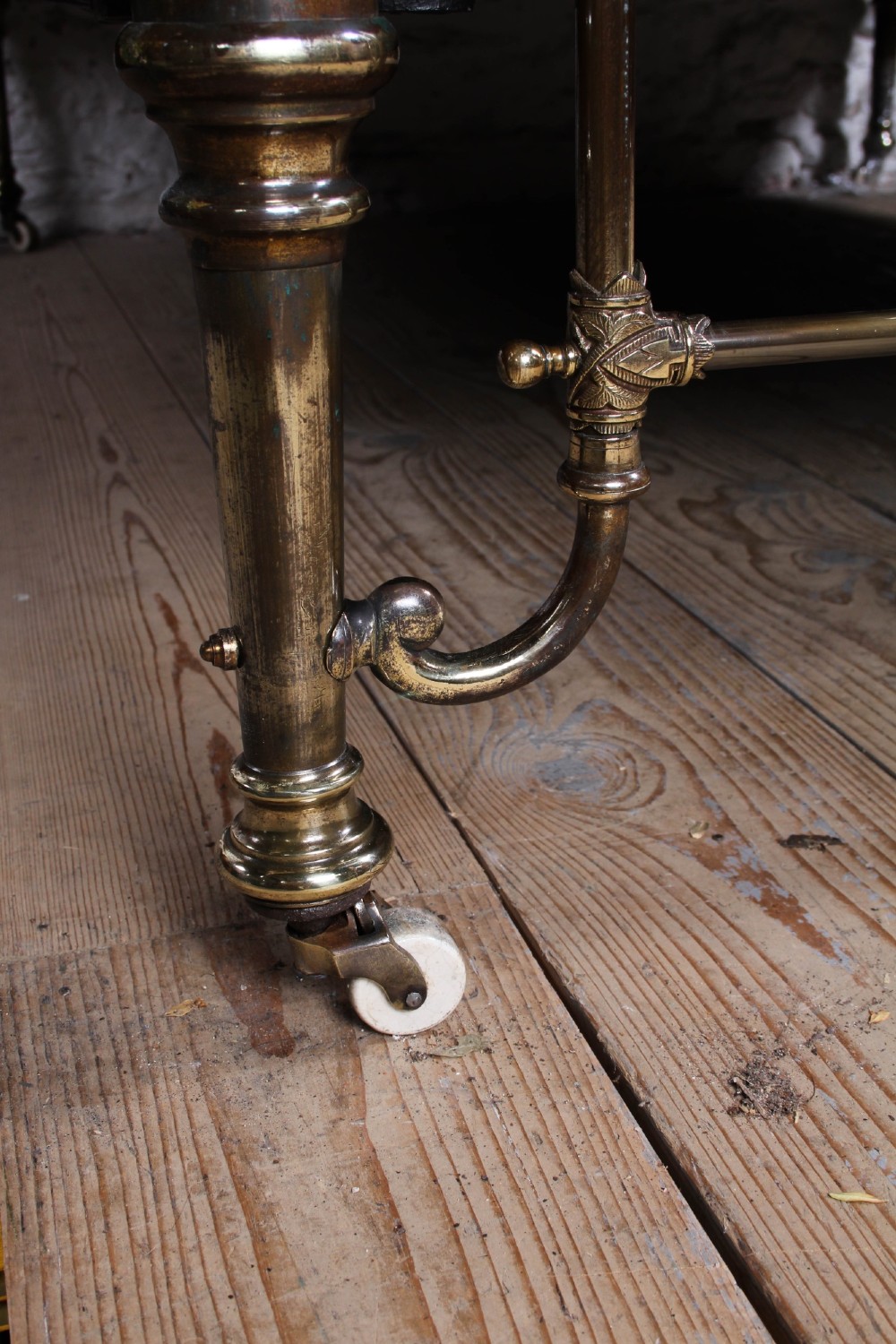 An antique Victorian brass king-size bedstead featuring vertical tubular spindles, decorative cast connectors, top rail ball finials, and original white ceramic castors. View IX