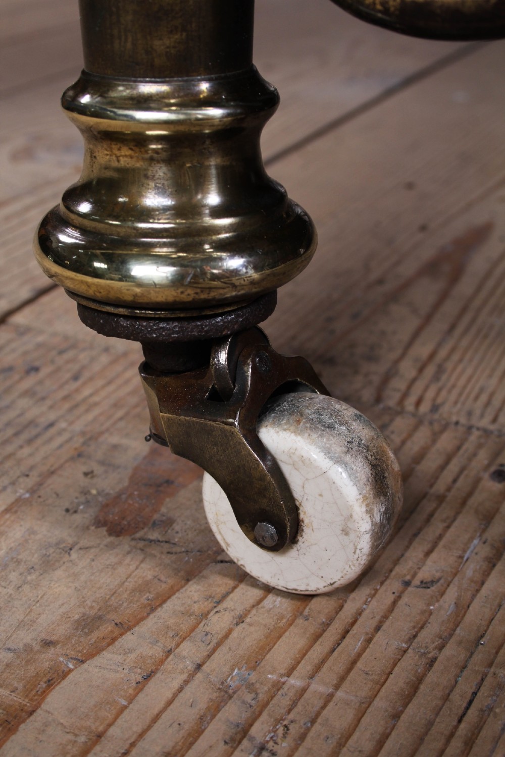 An antique Victorian brass king-size bedstead featuring vertical tubular spindles, decorative cast connectors, top rail ball finials, and original white ceramic castors. View X