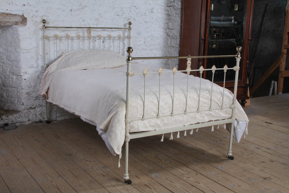 A Victorian cream-painted iron and brass three-quarter bedstead featuring vertical spindles, decorative cast motifs, and polished brass top rails with spherical finials. View II
