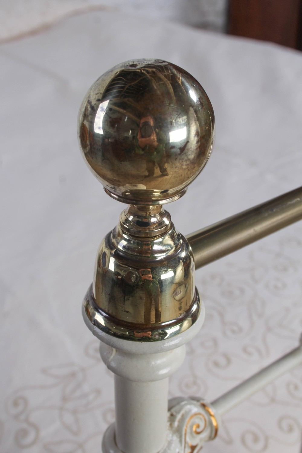 A Victorian cream-painted iron and brass three-quarter bedstead featuring vertical spindles, decorative cast motifs, and polished brass top rails with spherical finials. View V
