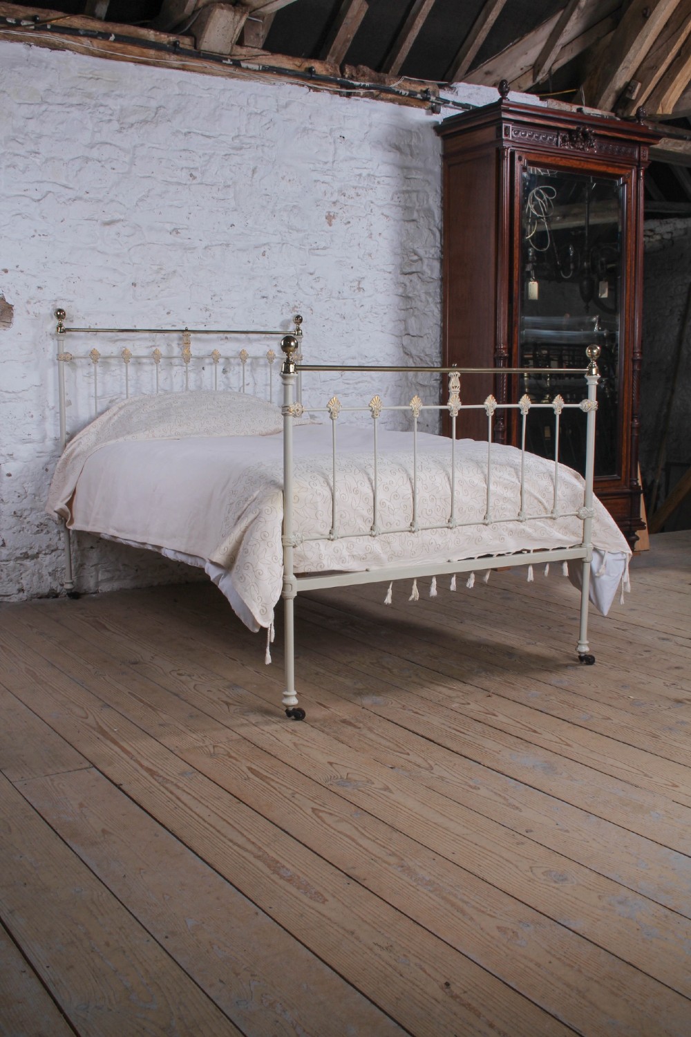 A Victorian cream-painted iron and brass three-quarter bedstead featuring vertical spindles, decorative cast motifs, and polished brass top rails with spherical finials. View VIII