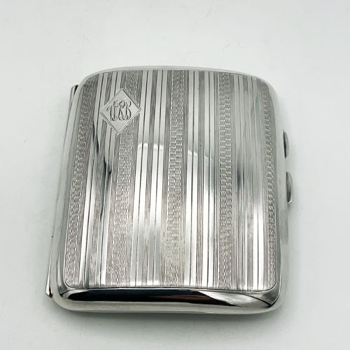fig 1. A curved rectangular sterling silver case featuring linear engine-turned pattern work and an engraved diamond monogram cartouche.