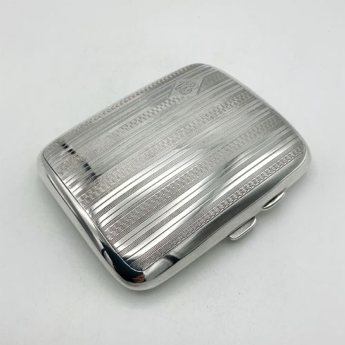fig 2. A curved rectangular sterling silver case featuring linear engine-turned pattern work and an engraved diamond monogram cartouche.