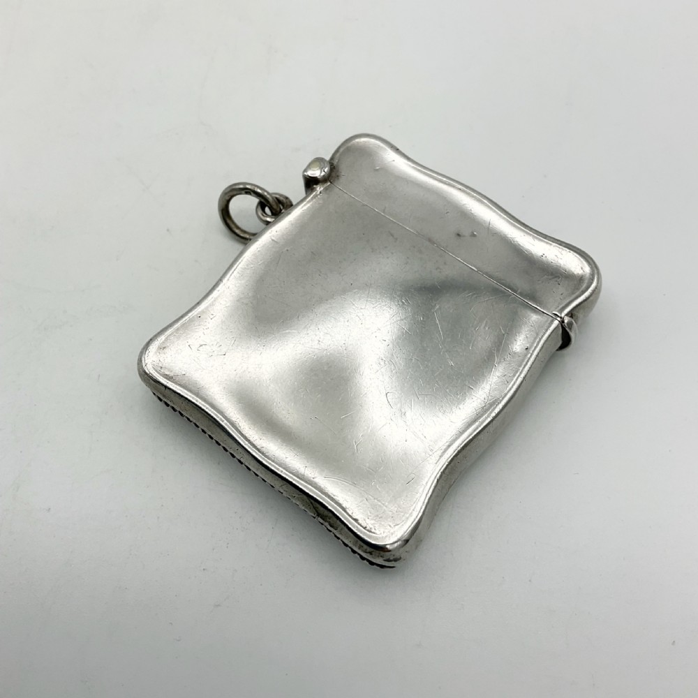 An Edwardian sterling silver vesta case with a contoured rectangular shape, side suspension ring, and hinged lid. View III