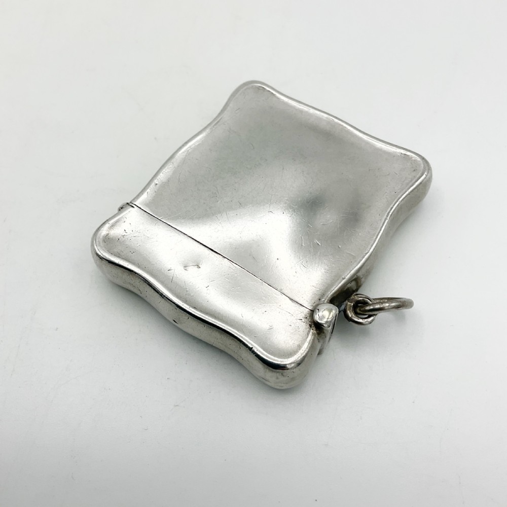 An Edwardian sterling silver vesta case with a contoured rectangular shape, side suspension ring, and hinged lid. View IV