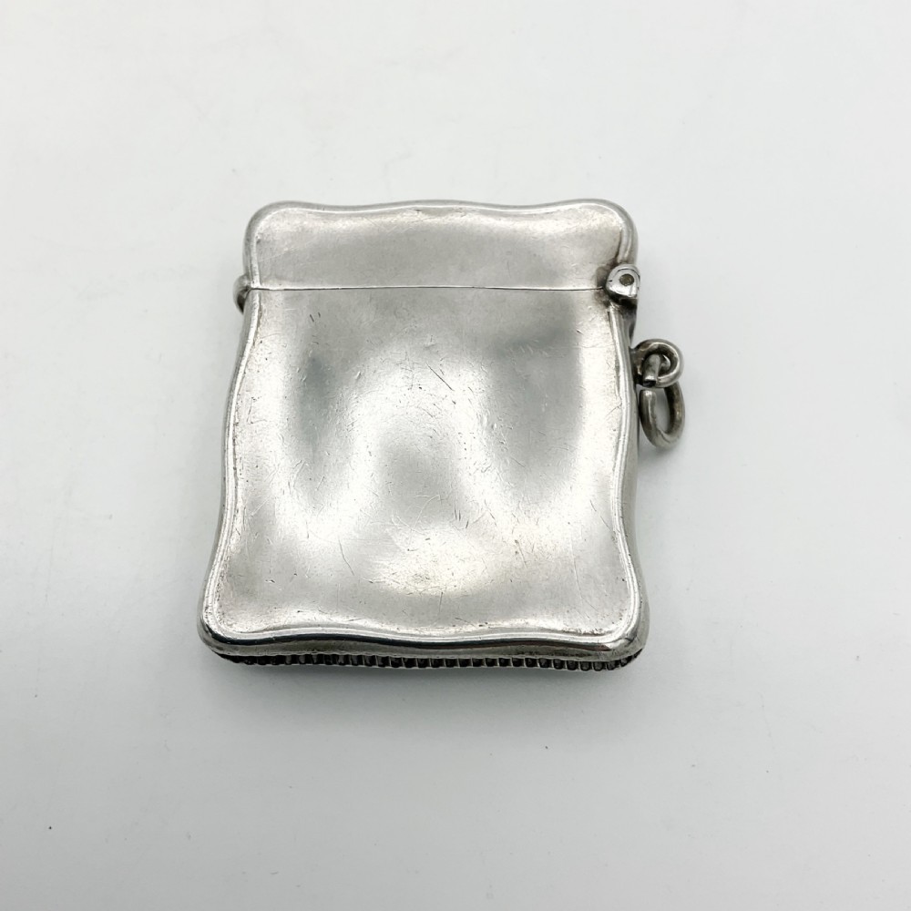 An Edwardian sterling silver vesta case with a contoured rectangular shape, side suspension ring, and hinged lid. View V