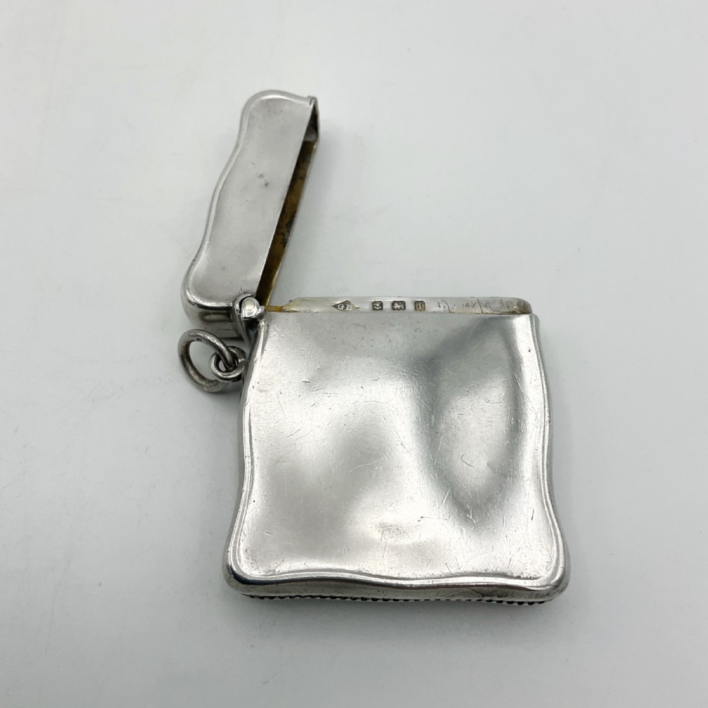 An Edwardian sterling silver vesta case with a contoured rectangular shape, side suspension ring, and hinged lid. View VIII