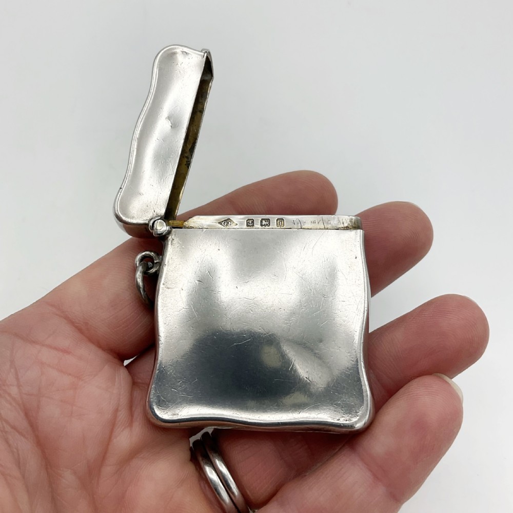 An Edwardian sterling silver vesta case with a contoured rectangular shape, side suspension ring, and hinged lid. View IX