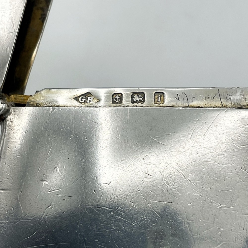 An Edwardian sterling silver vesta case with a contoured rectangular shape, side suspension ring, and hinged lid. View X