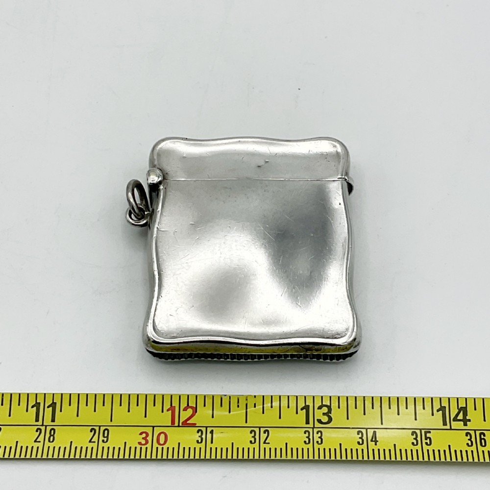 An Edwardian sterling silver vesta case with a contoured rectangular shape, side suspension ring, and hinged lid. View XI