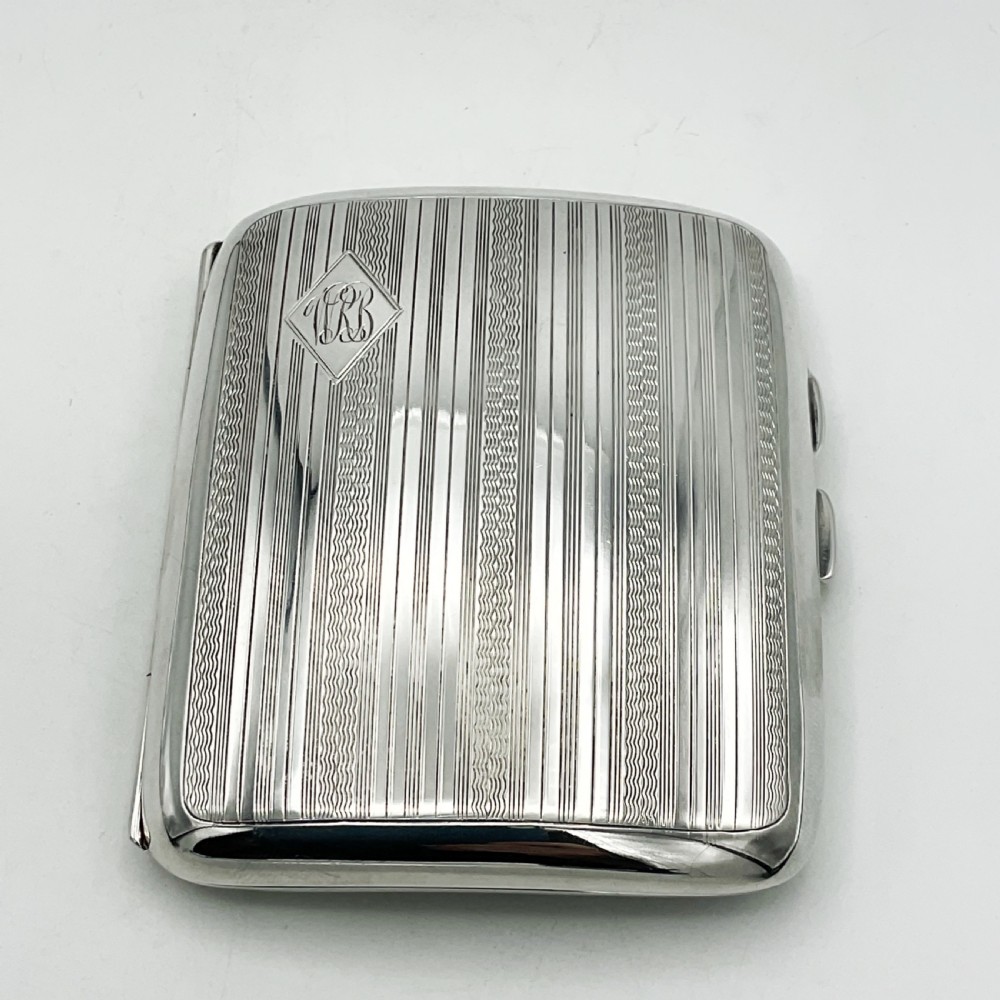 A curved rectangular sterling silver case featuring linear engine-turned pattern work and an engraved diamond monogram cartouche. View II