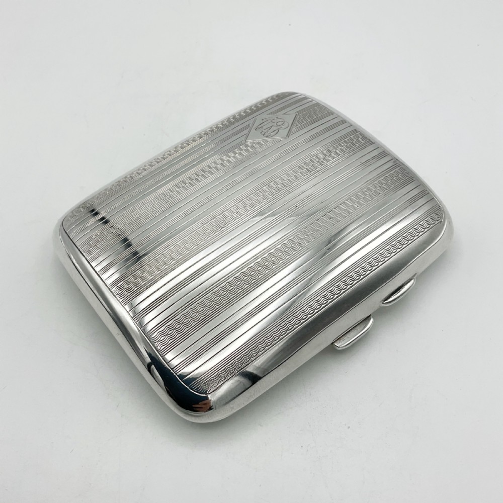 A curved rectangular sterling silver case featuring linear engine-turned pattern work and an engraved diamond monogram cartouche. View III