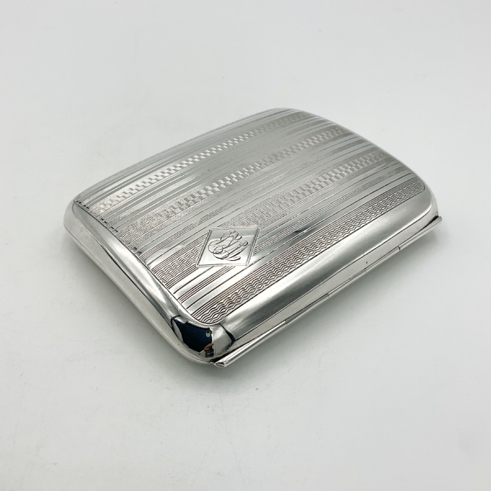 A curved rectangular sterling silver case featuring linear engine-turned pattern work and an engraved diamond monogram cartouche. View IV