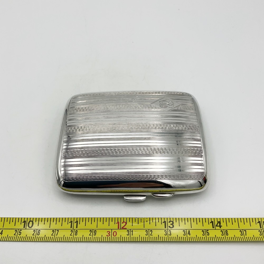 A curved rectangular sterling silver case featuring linear engine-turned pattern work and an engraved diamond monogram cartouche. View XIII