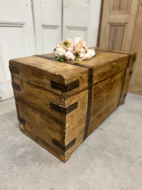 fig 1. A Victorian natural pine rectangular storage trunk featuring dark iron corner straps and metal banding across the hinged lid and body.