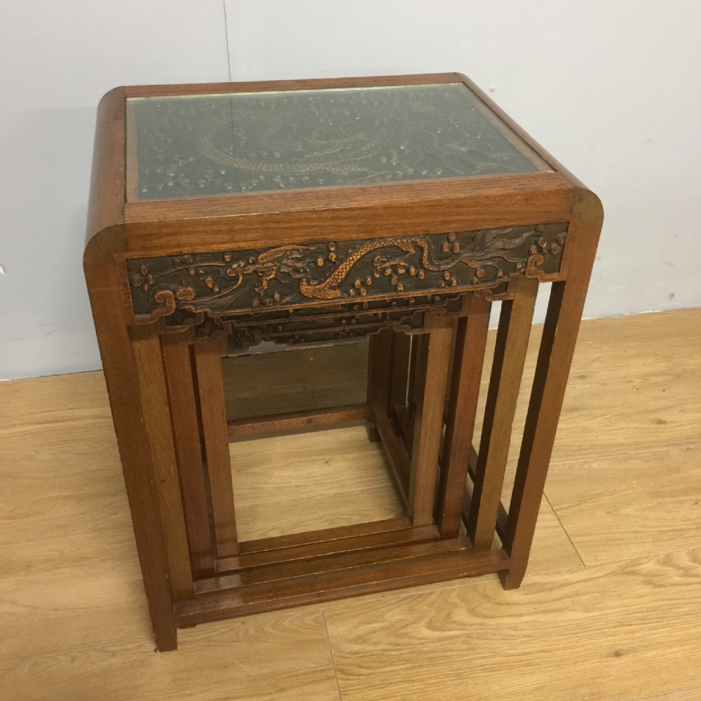 Chinoiserie hardwood nest of four tables with relief carved dragon decoration to the top and frieze