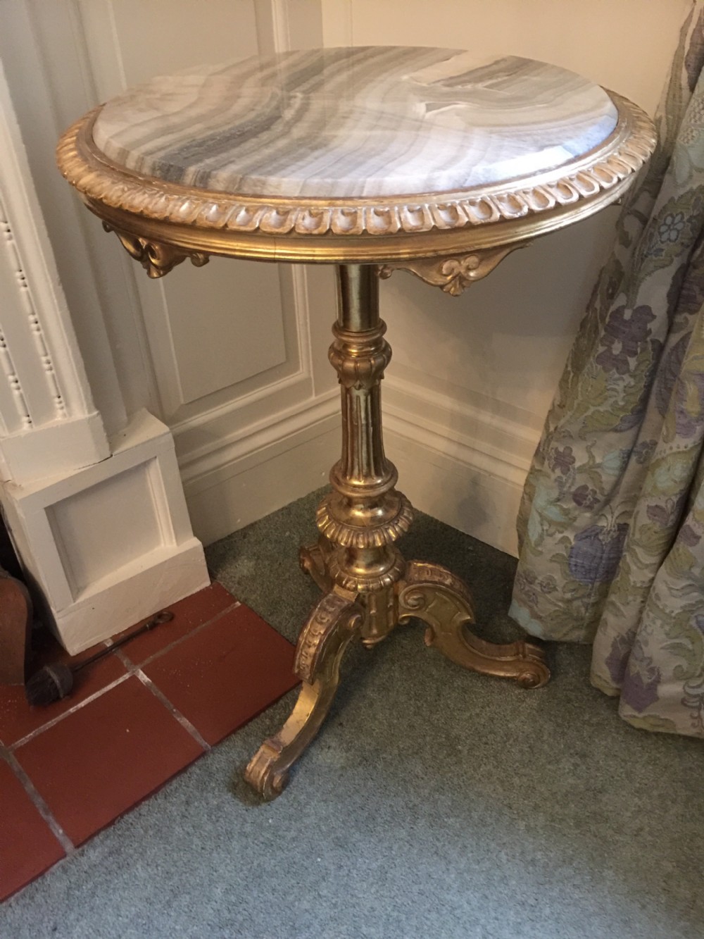 A 19th-century tripod table featuring a carved giltwood pedestal base, egg-and-dart moulding, and a circular variegated grey marble tabletop.
