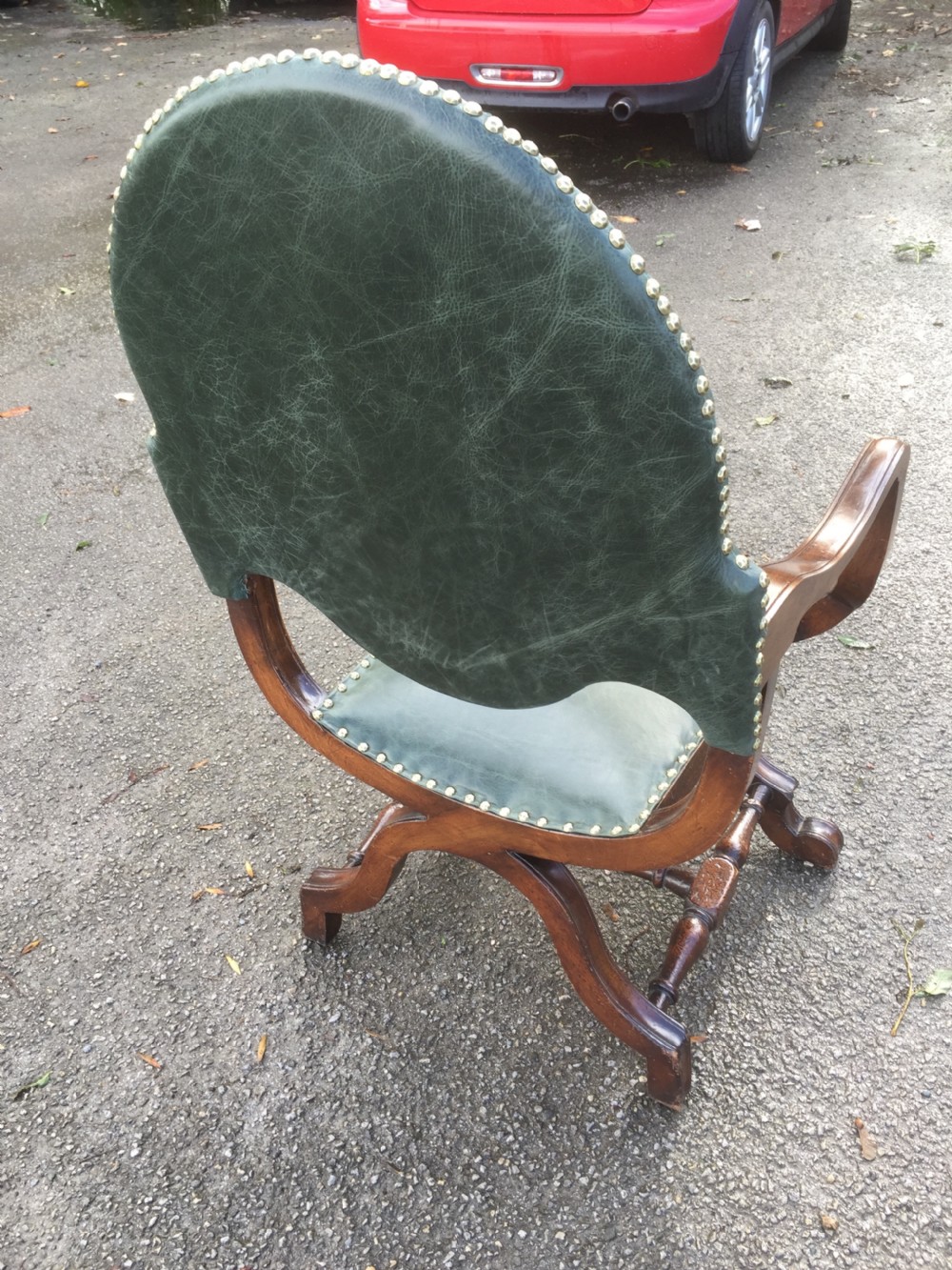 A nineteenth-century carved walnut X-frame armchair upholstered in dark olive green leather with brass stud details. View VIII