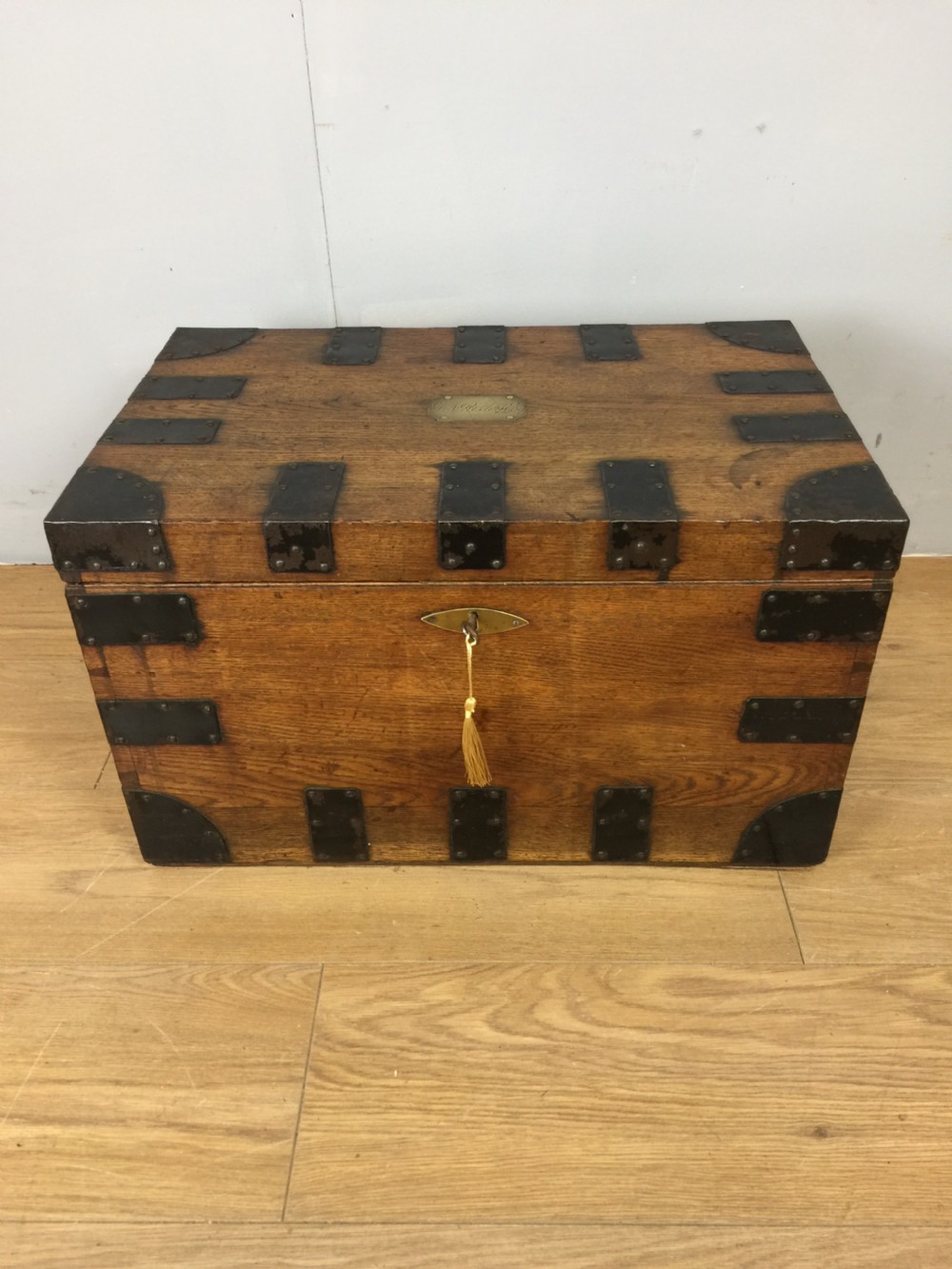 A nineteenth-century oak silver chest featuring black iron strap mounts, corner brackets, and a brass escutcheon with key.