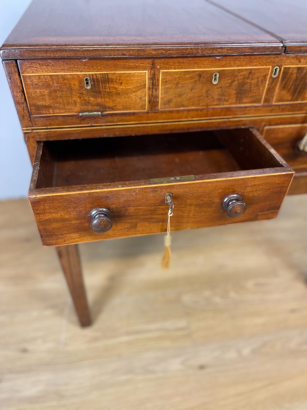 A Late Georgian inlaid mahogany collectors cabinet with square tapered legs, brass keyhole escutcheons, side knobs, and multiple drawers. View IV
