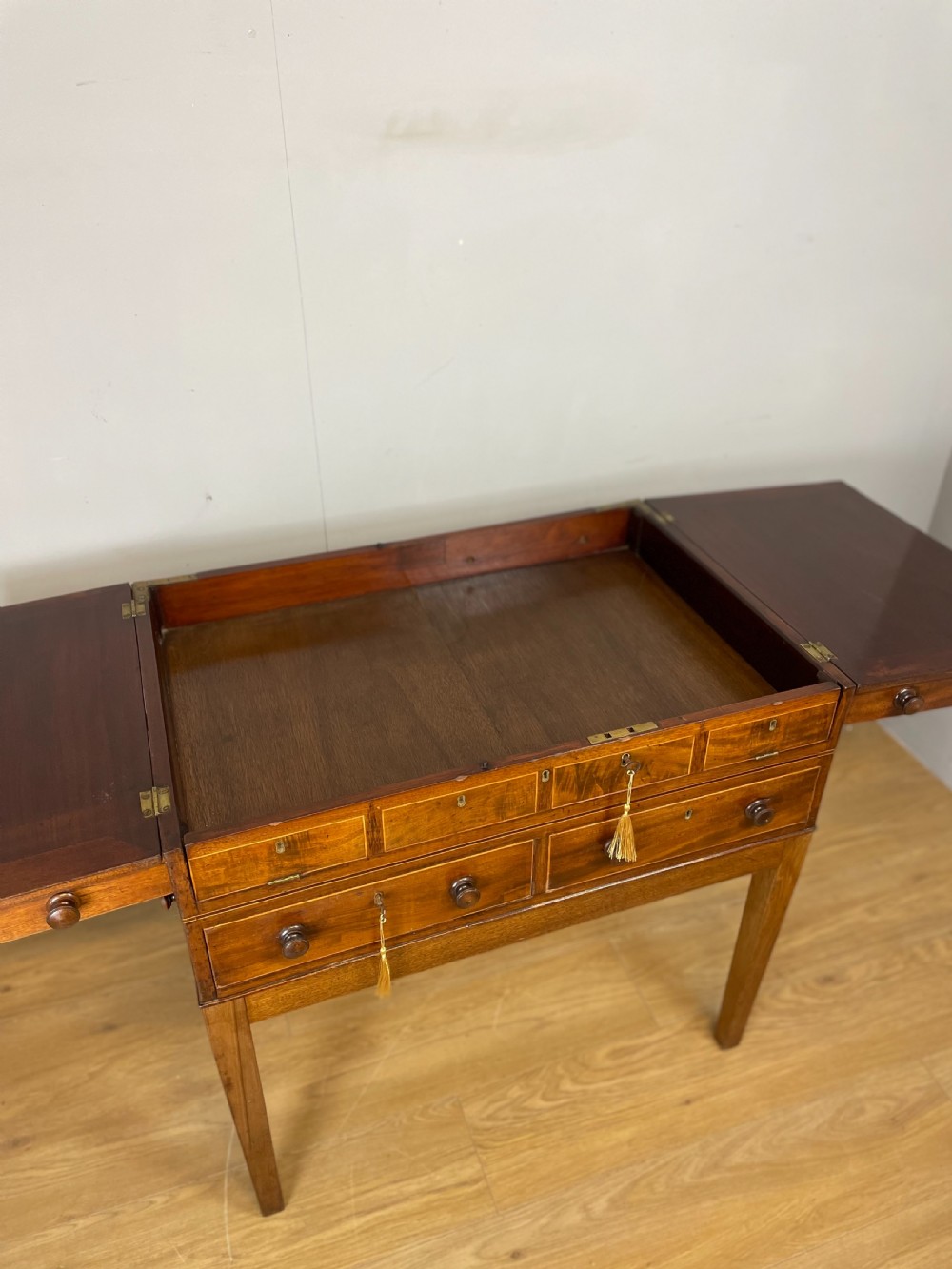 A Late Georgian inlaid mahogany collectors cabinet with square tapered legs, brass keyhole escutcheons, side knobs, and multiple drawers. View V
