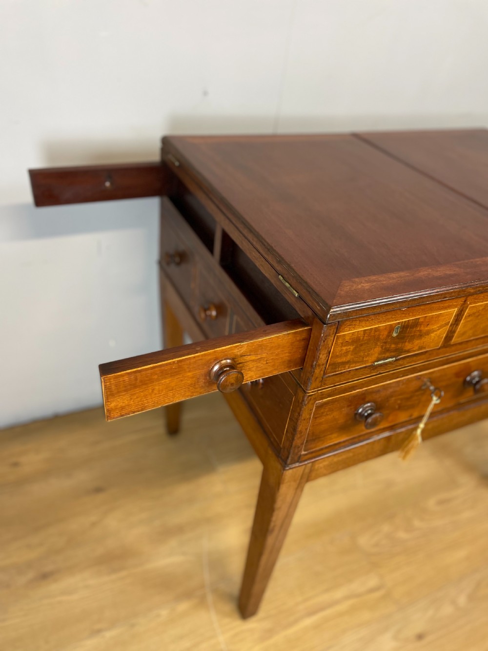 A Late Georgian inlaid mahogany collectors cabinet with square tapered legs, brass keyhole escutcheons, side knobs, and multiple drawers. View X