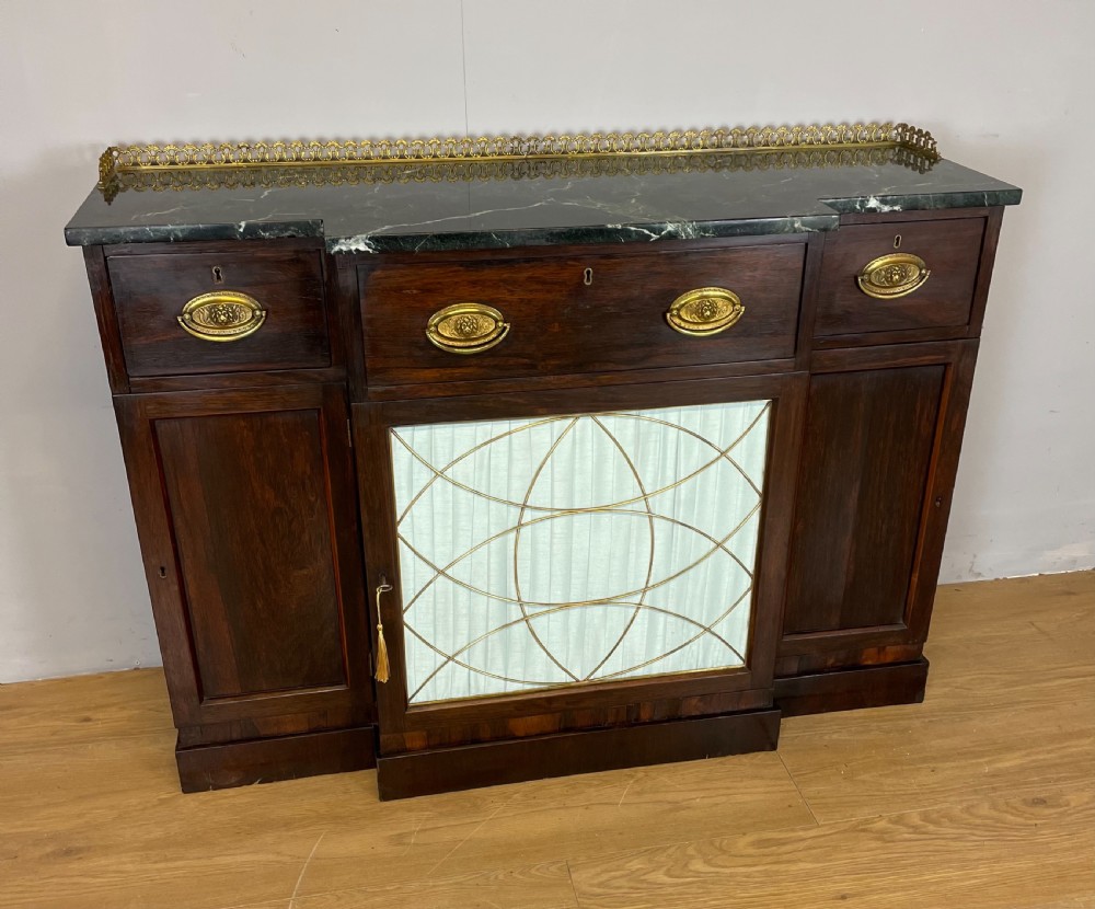 An early nineteenth-century Regency rosewood secretaire side cabinet featuring a dark green marble top with a brass gallery, a pleated fabric door panel, and brass handles. View II