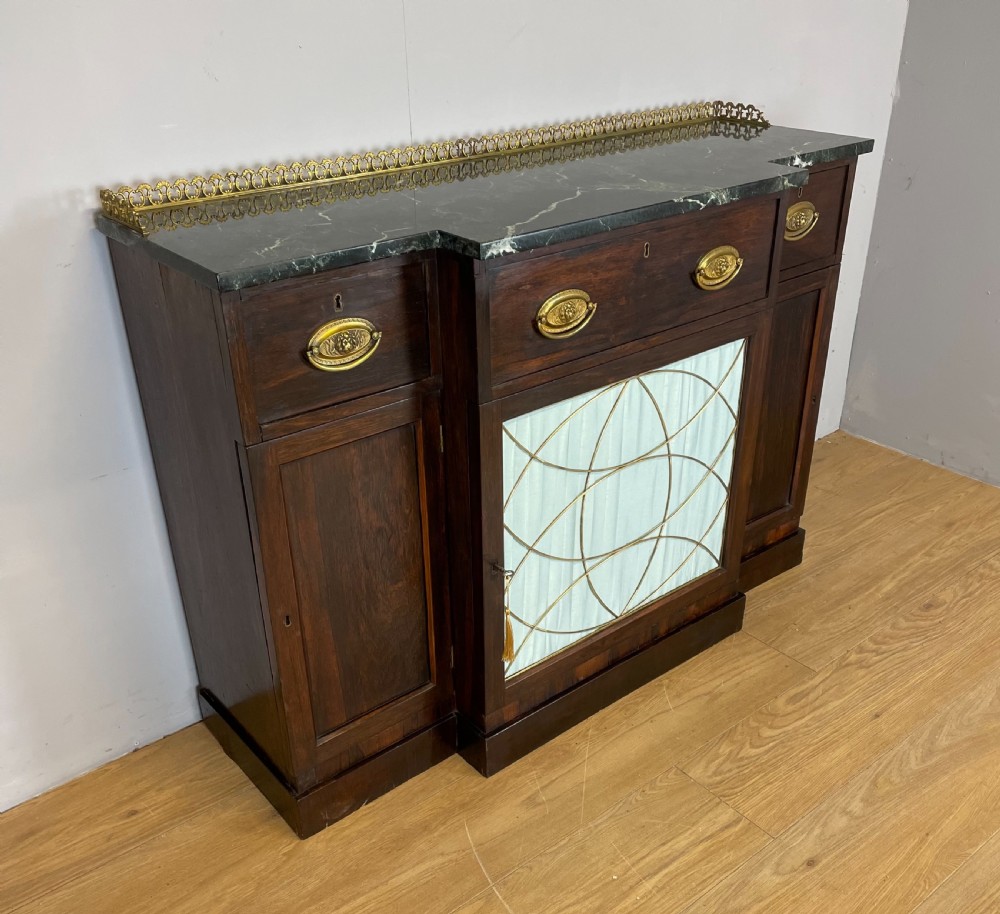 An early nineteenth-century Regency rosewood secretaire side cabinet featuring a dark green marble top with a brass gallery, a pleated fabric door panel, and brass handles. View III