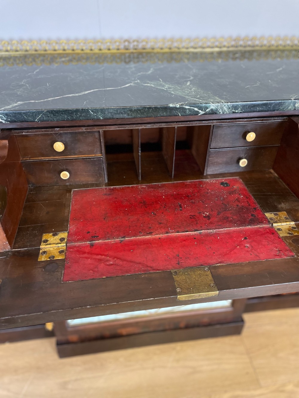 An early nineteenth-century Regency rosewood secretaire side cabinet featuring a dark green marble top with a brass gallery, a pleated fabric door panel, and brass handles. View IX