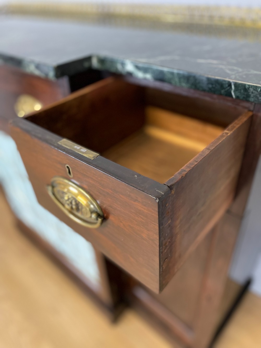 An early nineteenth-century Regency rosewood secretaire side cabinet featuring a dark green marble top with a brass gallery, a pleated fabric door panel, and brass handles. View X
