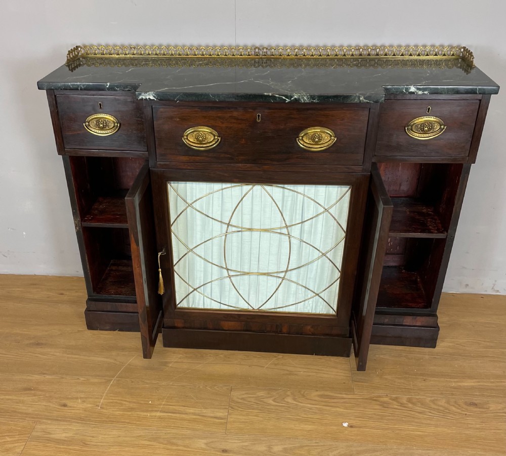 An early nineteenth-century Regency rosewood secretaire side cabinet featuring a dark green marble top with a brass gallery, a pleated fabric door panel, and brass handles. View XI