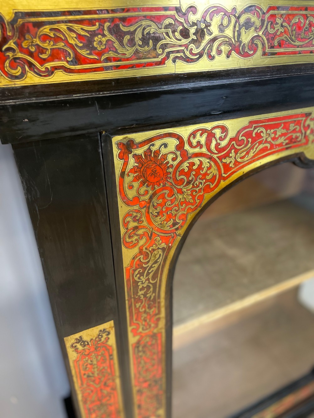 An ebonised nineteenth-century single-door display cabinet featuring brass and red tortoiseshell Boulle marquetry inlay around a glazed door and side panels. View III