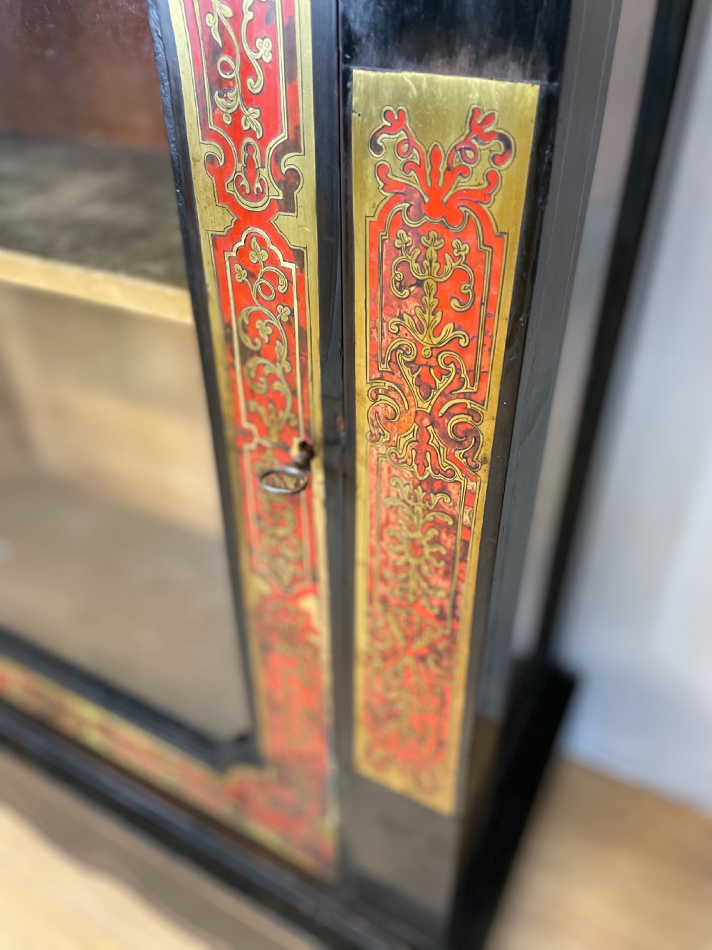 An ebonised nineteenth-century single-door display cabinet featuring brass and red tortoiseshell Boulle marquetry inlay around a glazed door and side panels. View XI