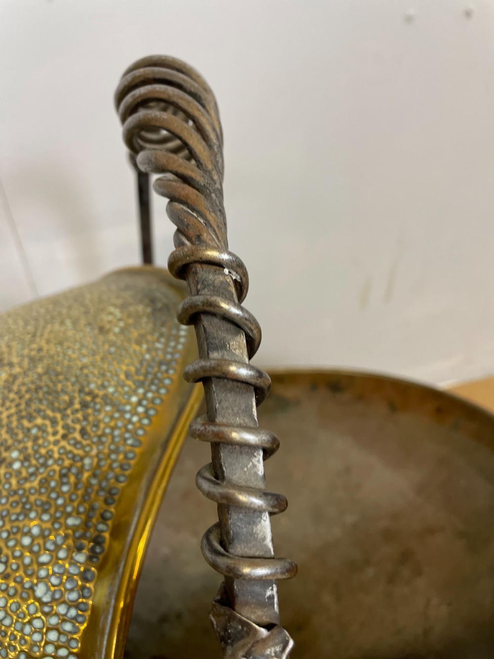 An Arts and Crafts style brass coal helmet with a textured hood, a wire-wrapped swing handle, a round pedestal base, and a matching hand shovel. View VII
