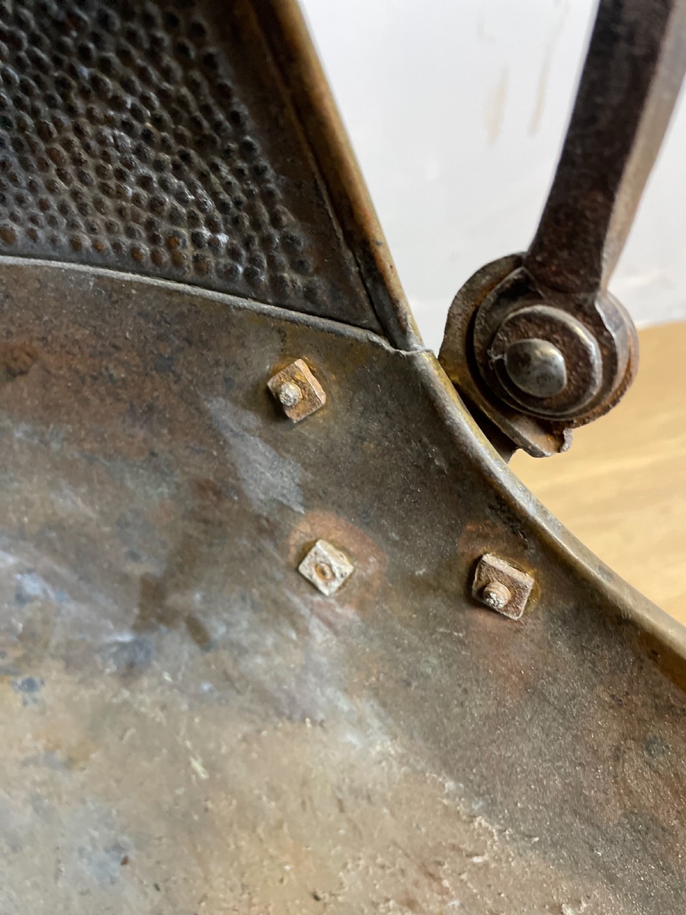 An Arts and Crafts style brass coal helmet with a textured hood, a wire-wrapped swing handle, a round pedestal base, and a matching hand shovel. View IX