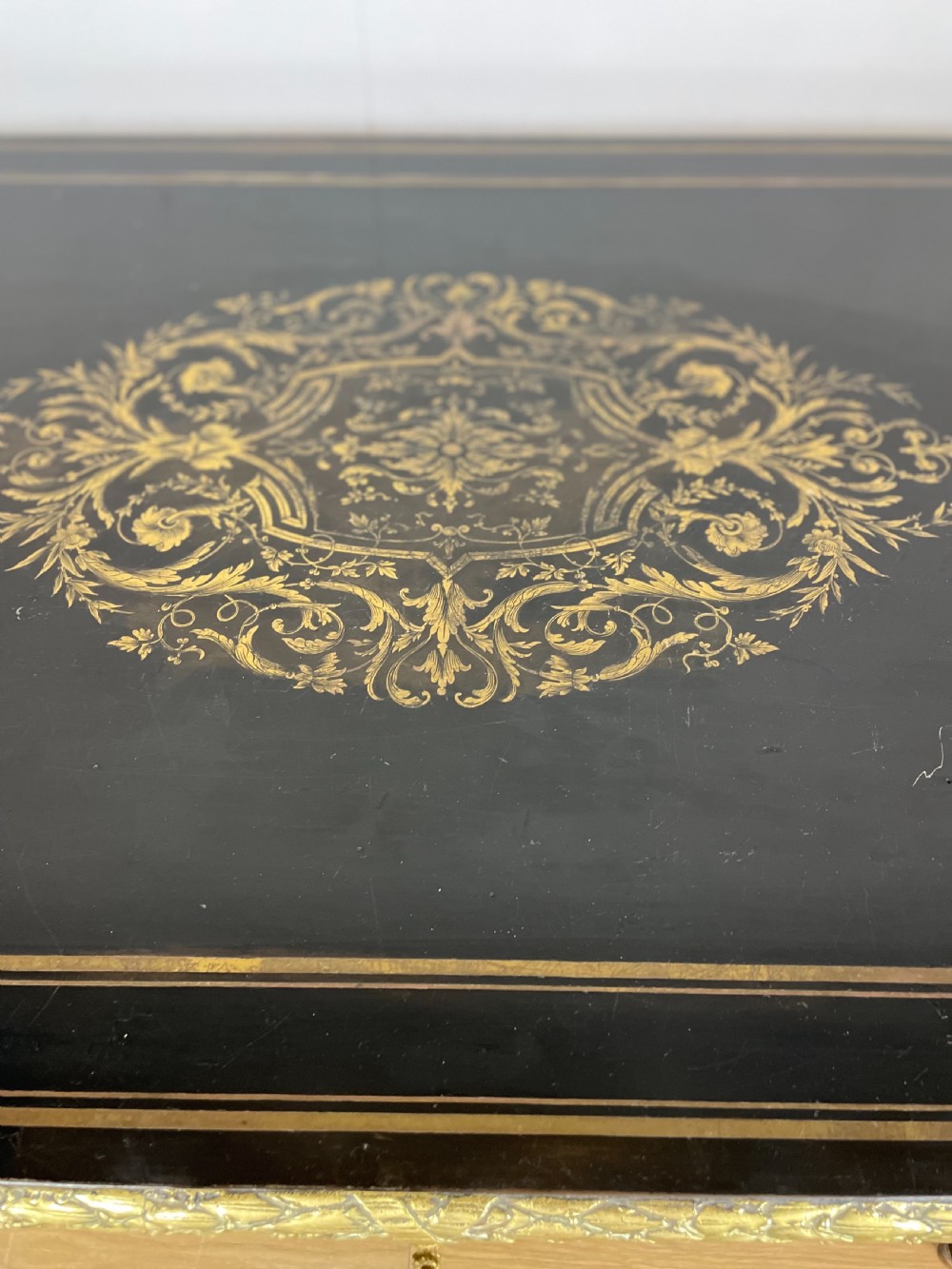 An ebonised nineteenth-century French writing table featuring gilt-bronze mounts, fluted tapered legs, a single central drawer, and a shaped top with central marquetry detailing. View II