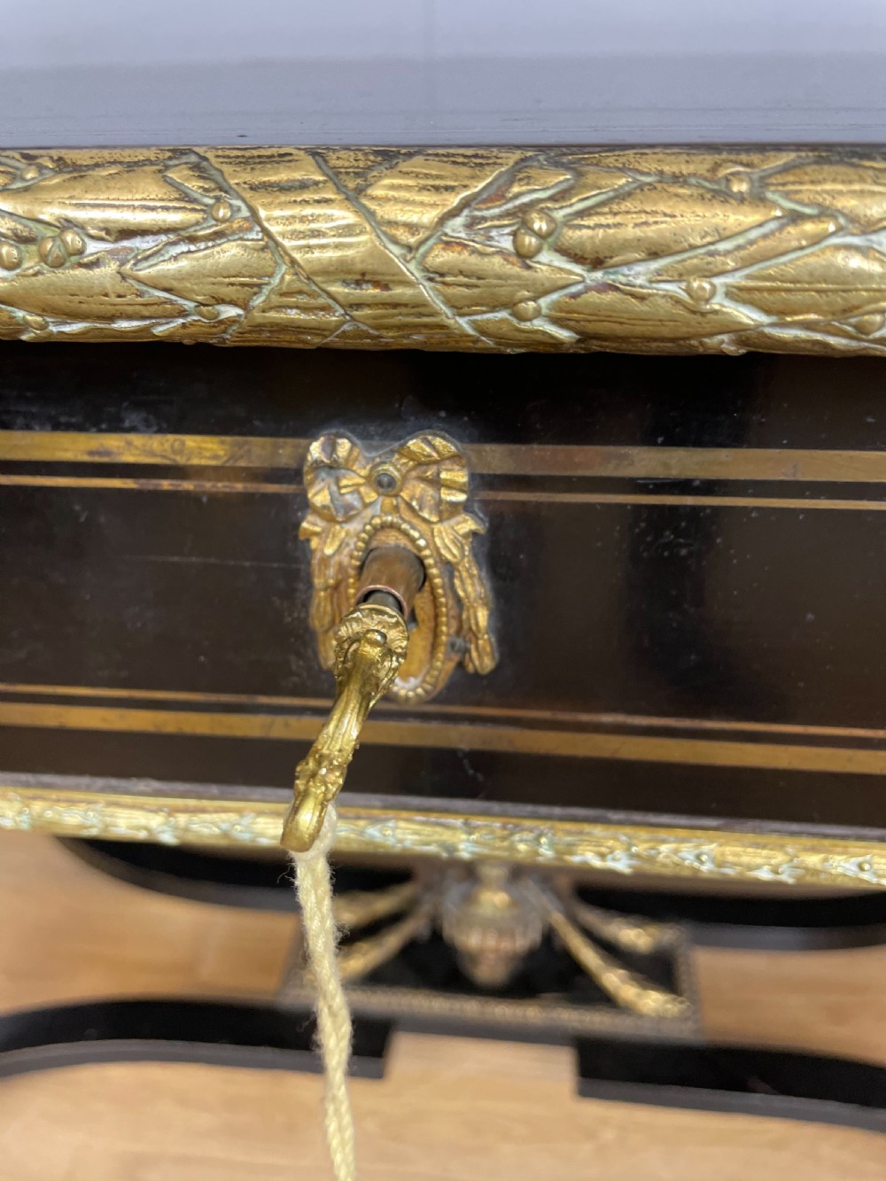 An ebonised nineteenth-century French writing table featuring gilt-bronze mounts, fluted tapered legs, a single central drawer, and a shaped top with central marquetry detailing. View XII