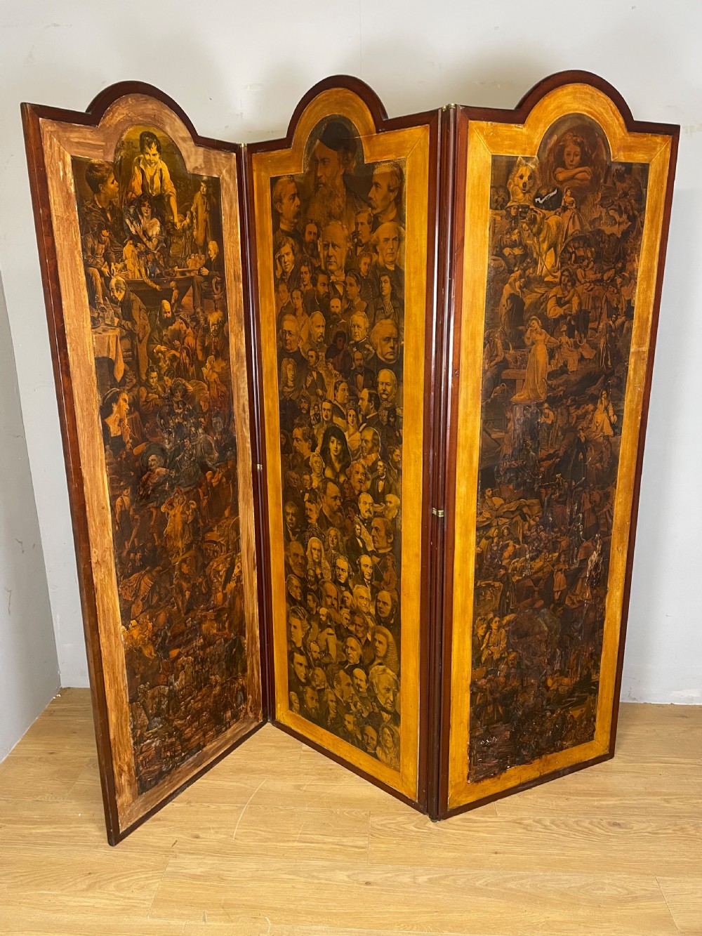 A three-panel wooden folding screen featuring dense Victorian decoupage artwork made of black and white engravings under a clear varnish finish.
